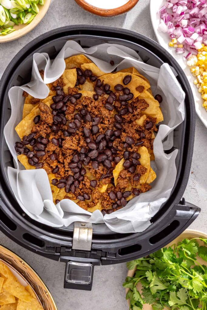 Ground beef, black beans, cheese, peppers, corn, and jalapeños layered over tortilla chips