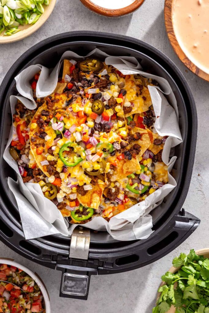 Air fryer nachos with melted cheese, seasoned beef, beans, and vegetables