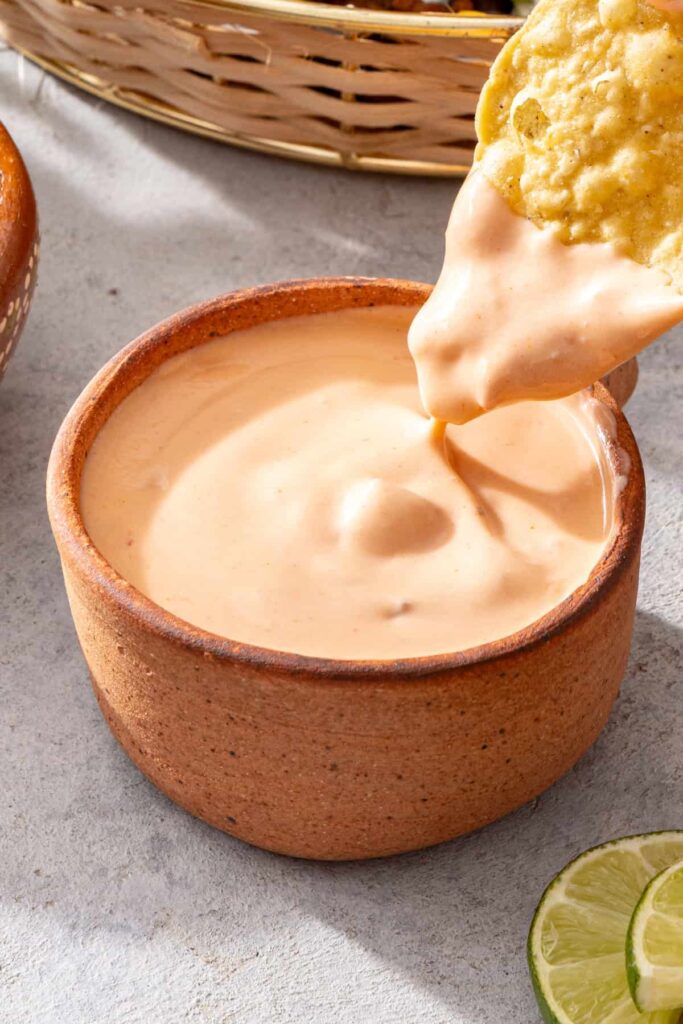 Hand dipping a tortilla chip into high-protein cottage cheese queso