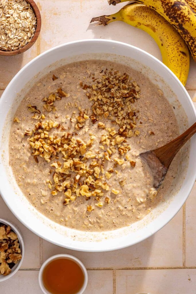 Chopped walnuts being folded into the banana bread baked oatmeal mixture