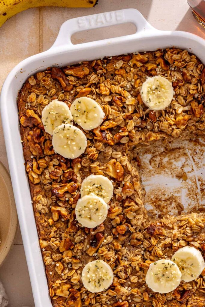 Overhead view of baked oatmeal with banana slices and maple walnut crumble in a casserole dish