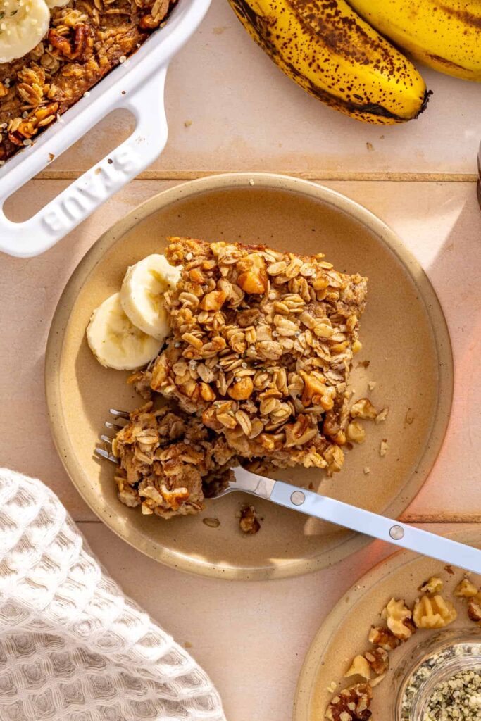 Slice of baked oatmeal with banana and fork on a plate