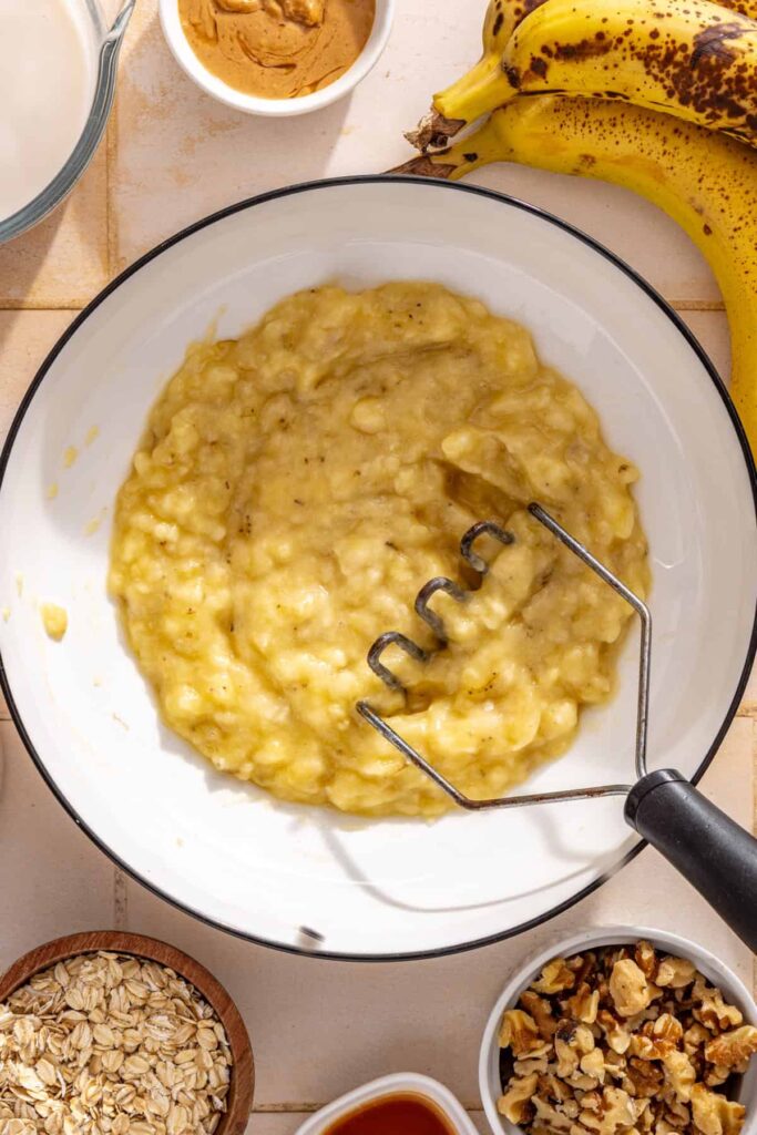 Ripe bananas being mashed in a bowl for banana bread baked oatmeal