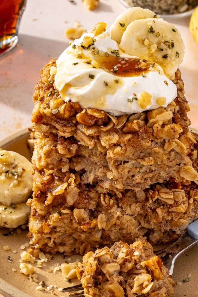 close-up of stack of banana bread baked oatmeal slices with yogurt and maple syrup drizzle toppings