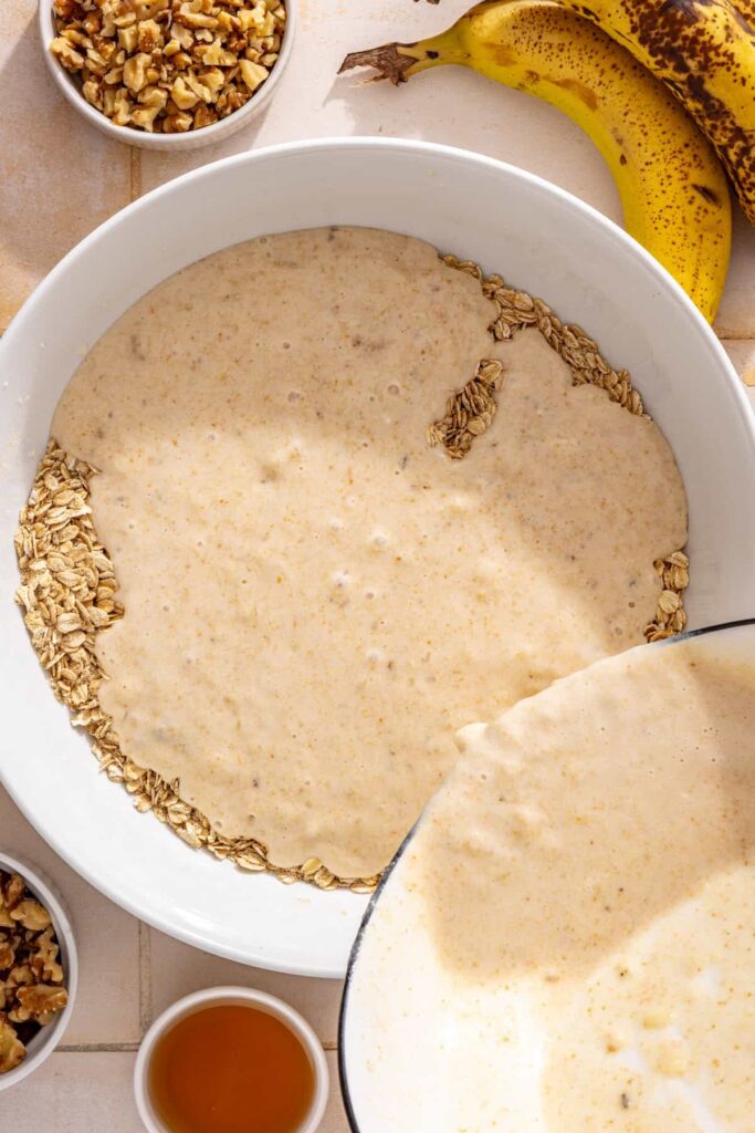 Wet banana mixture being stirred into the dry ingredients for banana bread baked oatmeal
