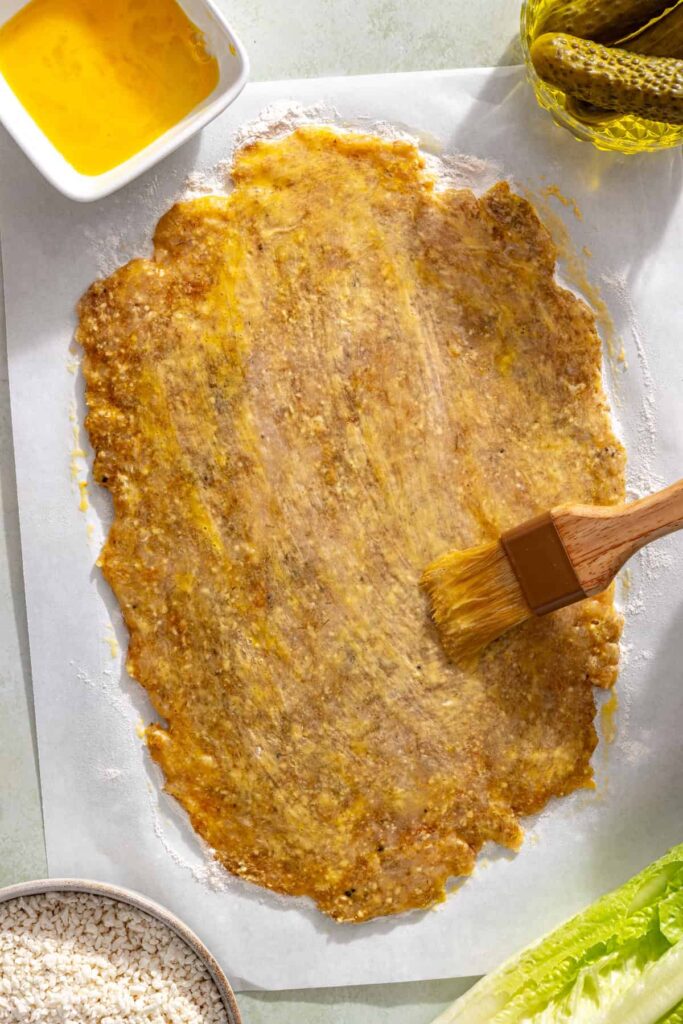 Brushing flattened chicken cutlet with egg wash before breading