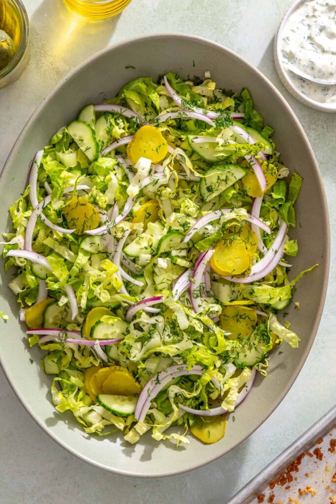 Shredded romaine, cucumber, pickles, red onion, and dill for creamy dill salad