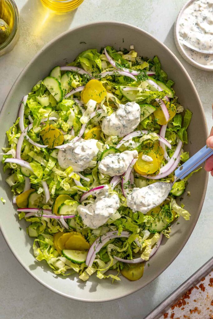 Adding creamy Greek yogurt pickle ranch to the shredded romaine salad