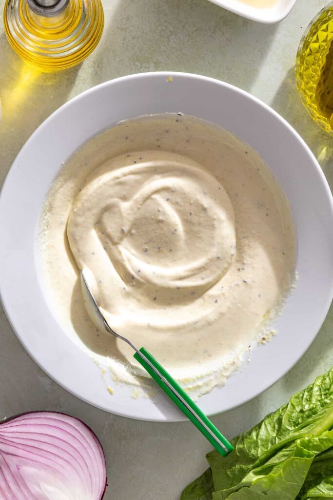 Mixing Greek yogurt pickle ranch ingredients until smooth and creamy