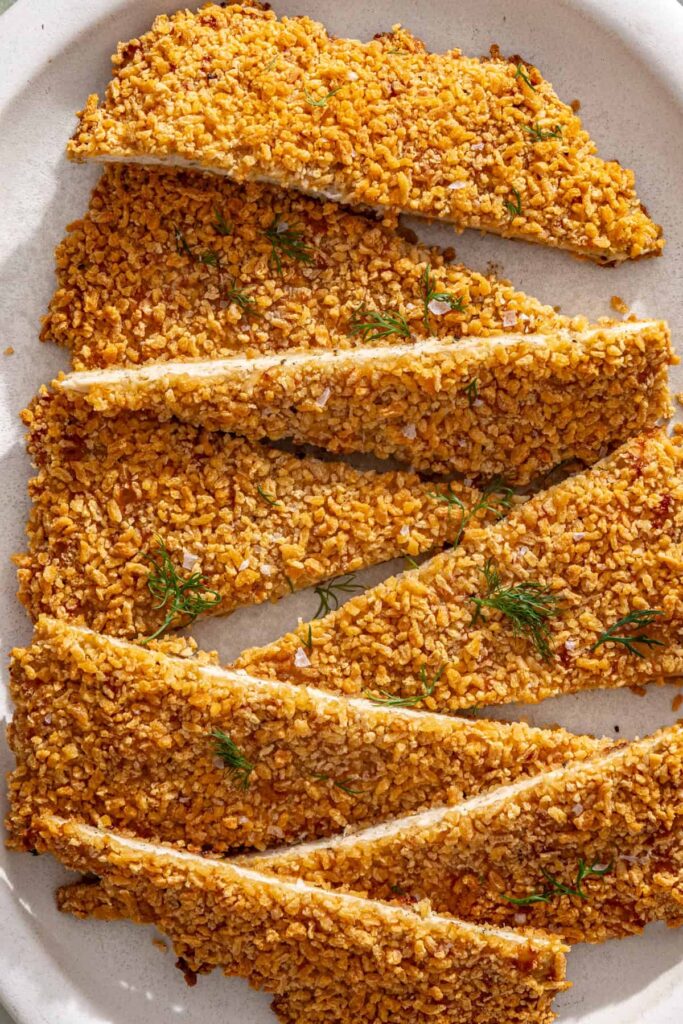 close-up of Golden baked chicken cutlet sliced and served family-style on a platter