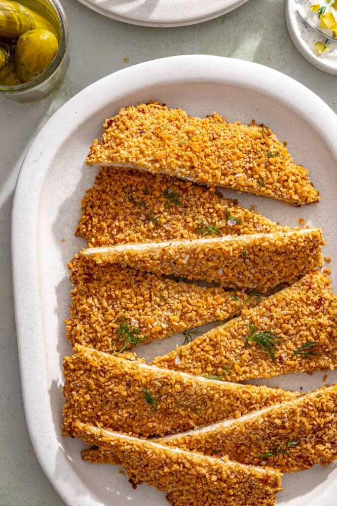 Giant pickle chicken cutlet sliced into crispy strips on a styled serving platter