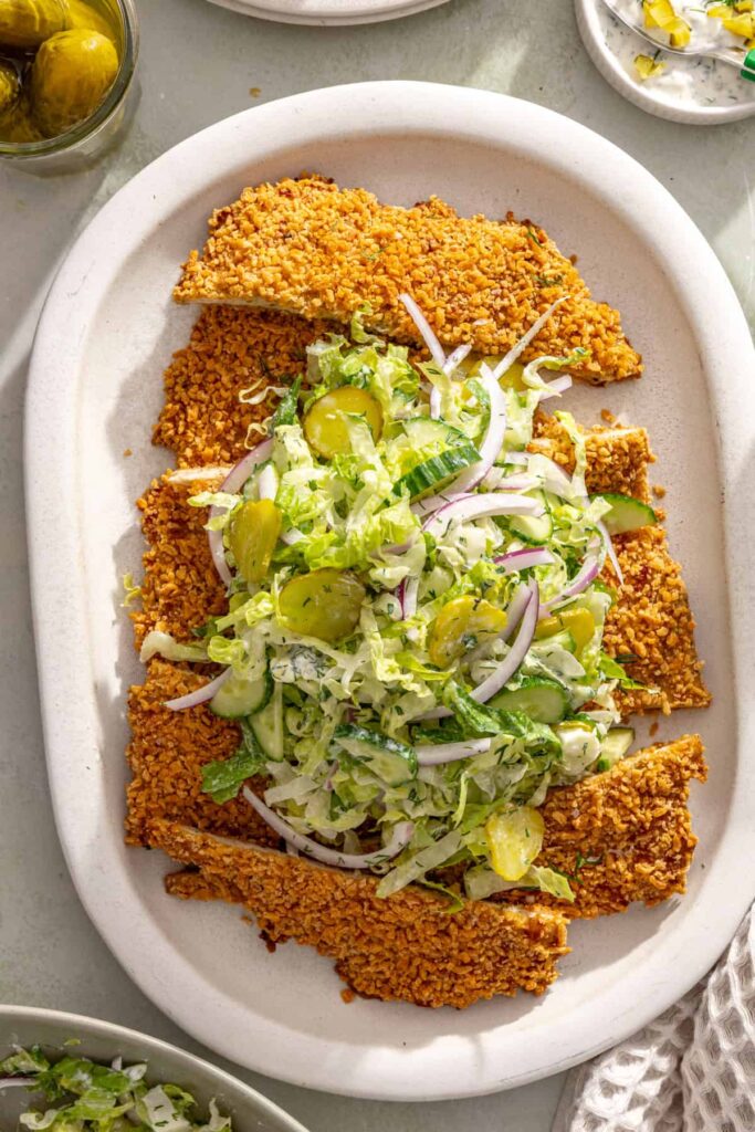 Crispy sliced pickle chicken cutlet topped with creamy dill salad