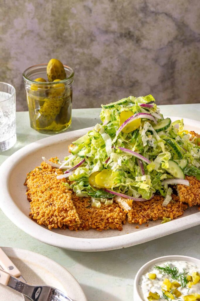 Crispy giant dill pickle chicken cutlet topped with creamy shredded romaine salad