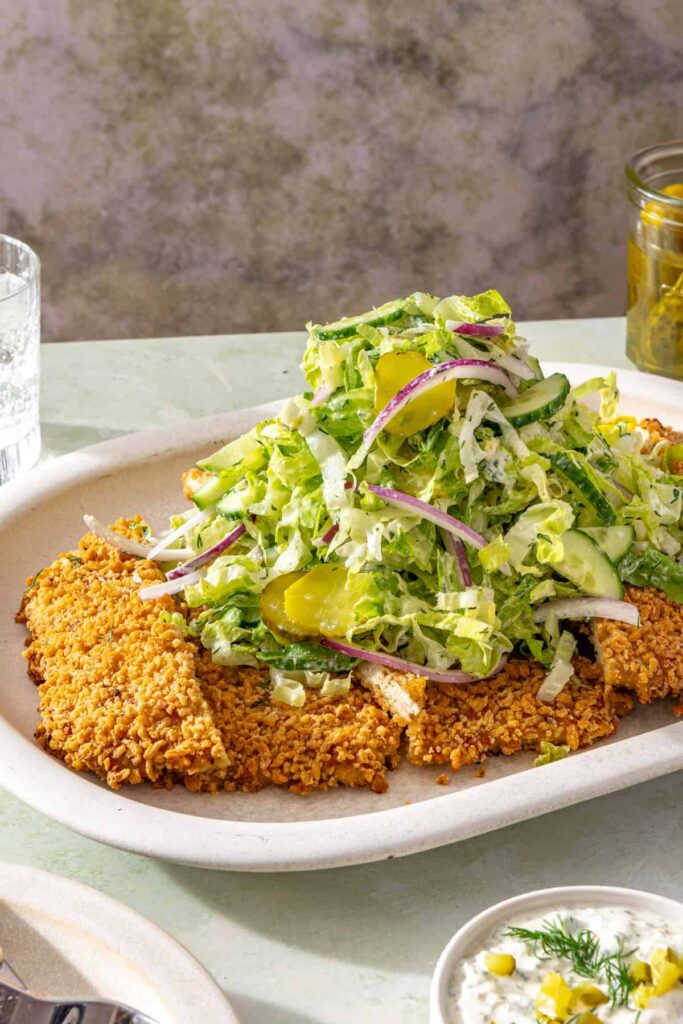 Crispy panko-crusted chicken cutlet topped with cucumber and dill pickle salad