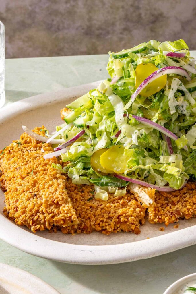 Golden crispy chicken cutlet topped with creamy shredded romaine and dill