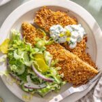 Overhead giant dill pickle chicken cutlet sliced and served with creamy dill salad and pickle ranch