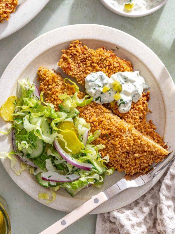 Overhead giant dill pickle chicken cutlet sliced and served with creamy dill salad and pickle ranch