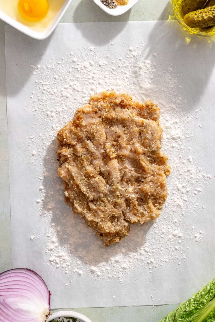 Seasoned ground chicken placed on cassava-floured parchment paper