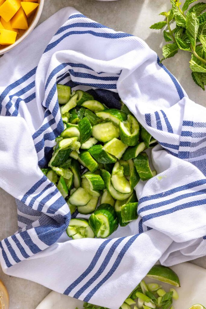 Squeezing excess water from salted smashed cucumbers