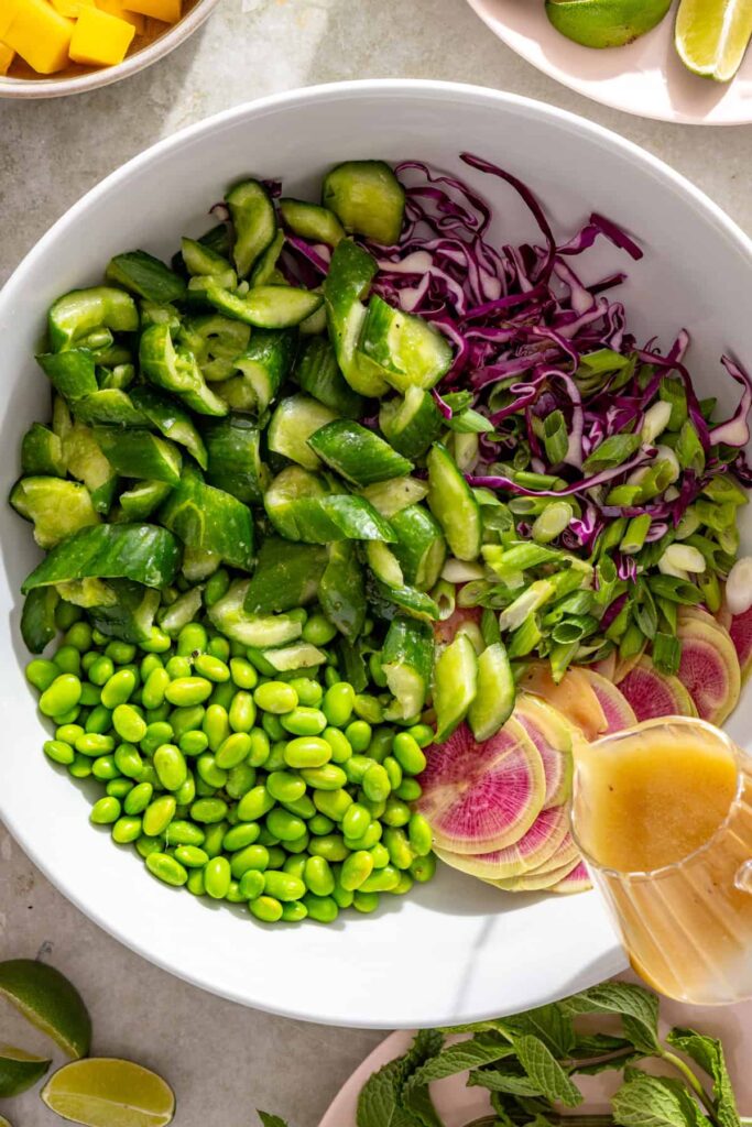 Adding sesame lime dressing to smashed cucumber salad
