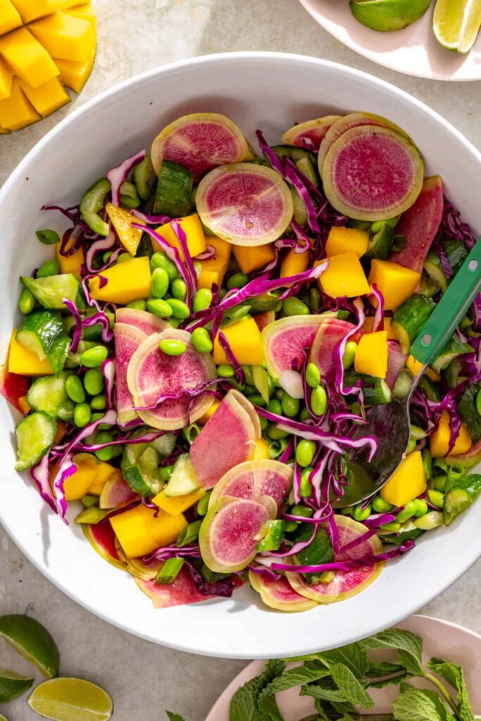 Colorful cucumber mango salad ingredients combined in a large bowl