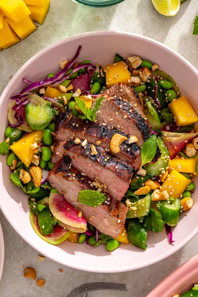 overhead shot of ginger sesame flank steak with smashed cucumber mango salad