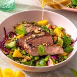 Ginger sesame flank steak with smashed cucumber mango salad drizzled with sesame lime dressing