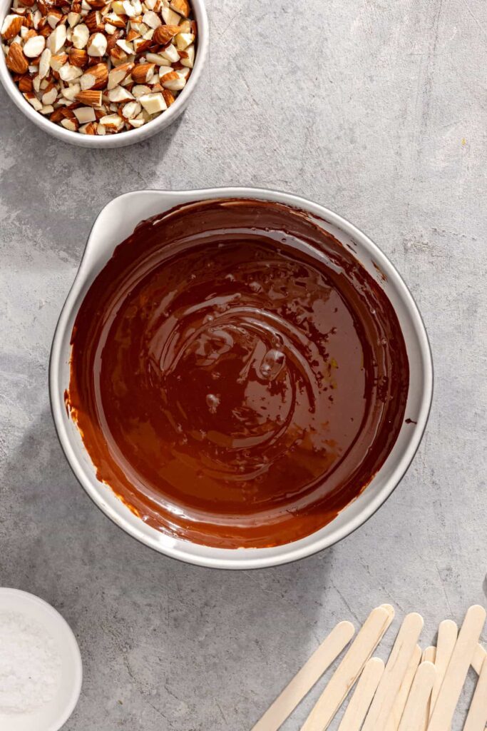 Smooth melted chocolate shell prepared for dipping frozen banana ice cream bars