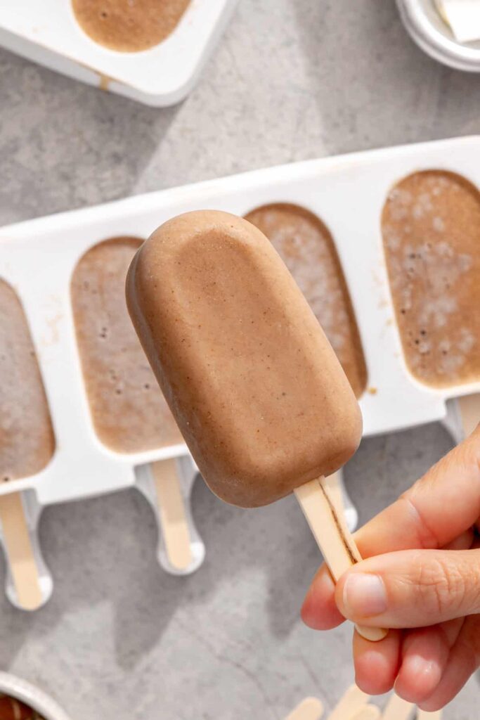 Undecorated homemade banana ice cream bar held in hand showing its creamy frozen texture