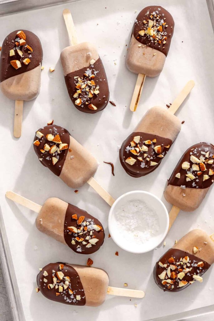Chocolate-coated homemade ice cream bars topped with chopped nuts and flaky sea salt