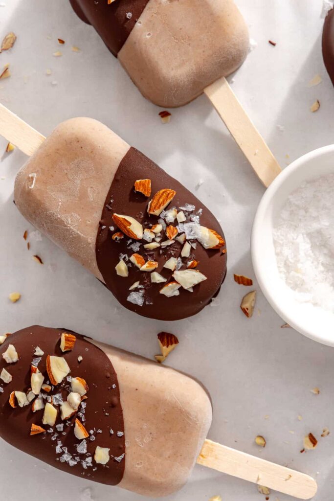 Close-up of chocolate-coated homemade ice cream bars topped with chopped nuts and flaky sea salt