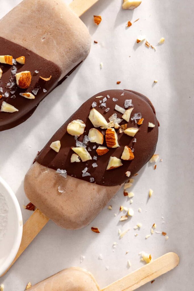 close up of a homemade healthy ice cream bar with a chocolate shell and chopped nuts