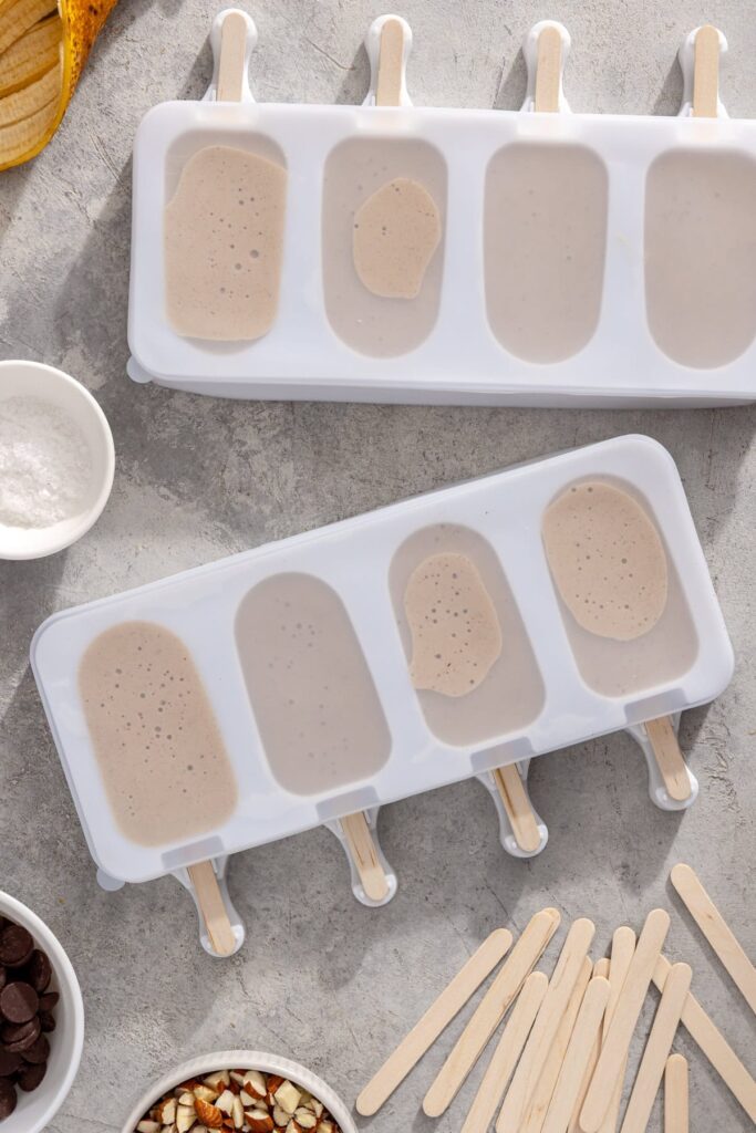 Ice cream bar molds filled with creamy banana peanut butter mixture ready to go into the freezer