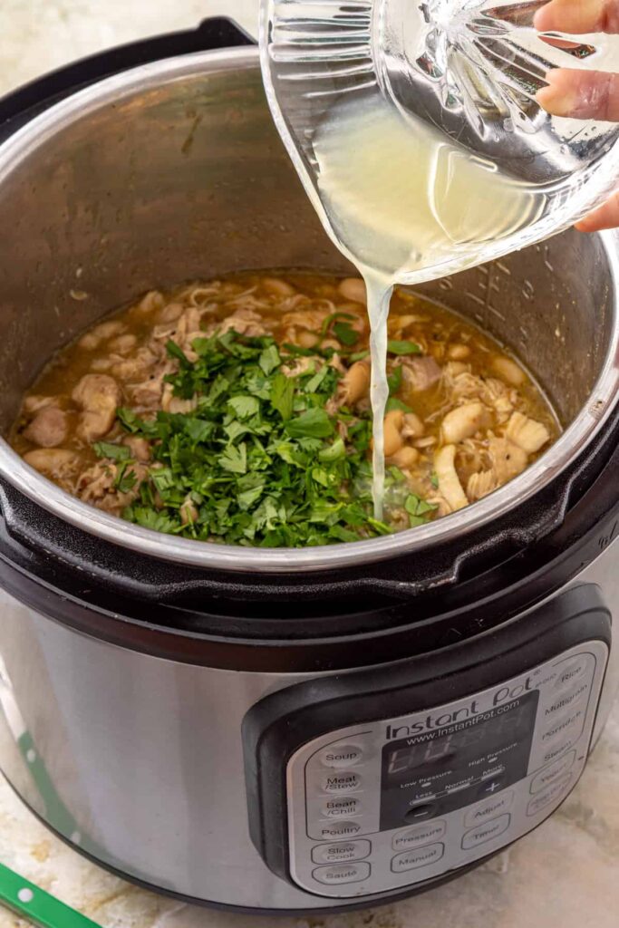 Fresh lime juice being added to chicken and white beans in green enchilada sauce