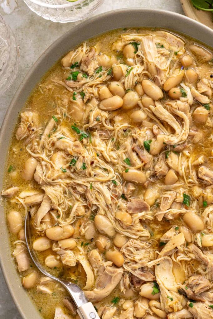 Close-up of shredded green enchilada chicken and white beans in green enchilada sauce