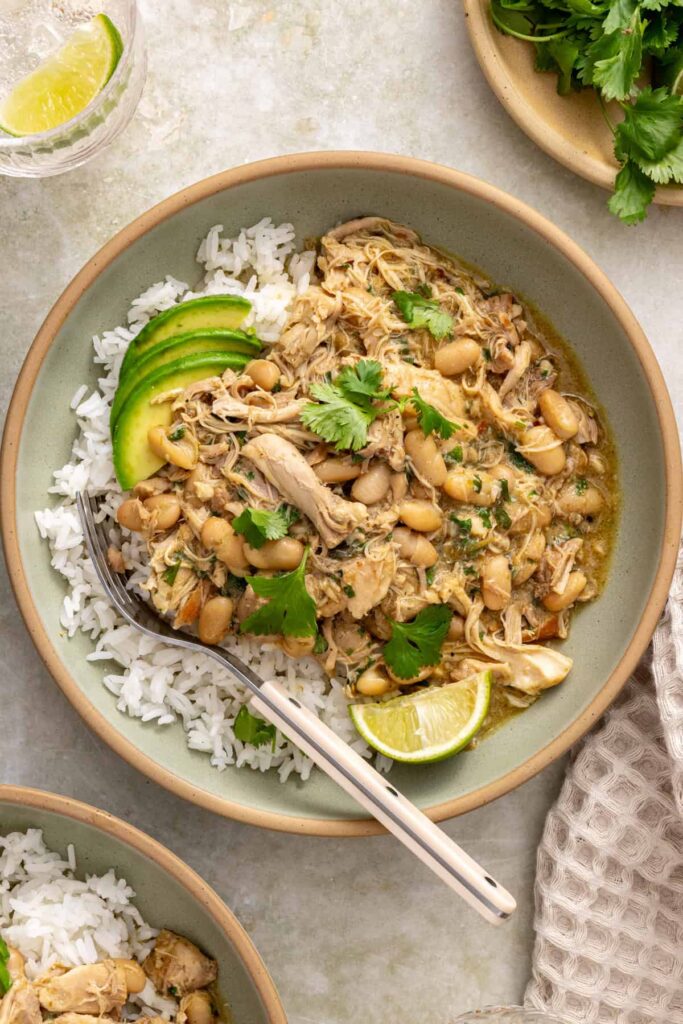 Green enchilada chicken over rice topped with fresh cilantro and sliced avocado