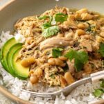 Green enchilada chicken and white beans served over rice with avocado, cilantro, and fresh lime juice
