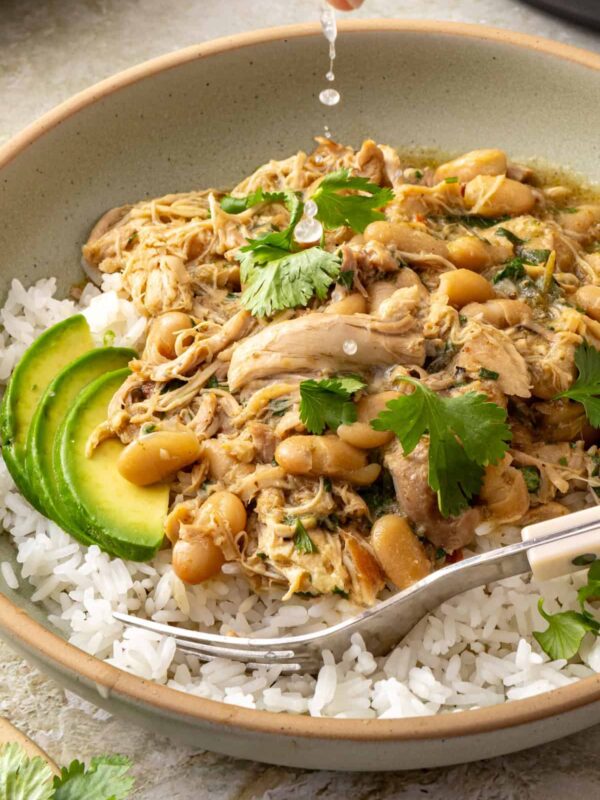 Green enchilada chicken and white beans served over rice with avocado, cilantro, and fresh lime juice