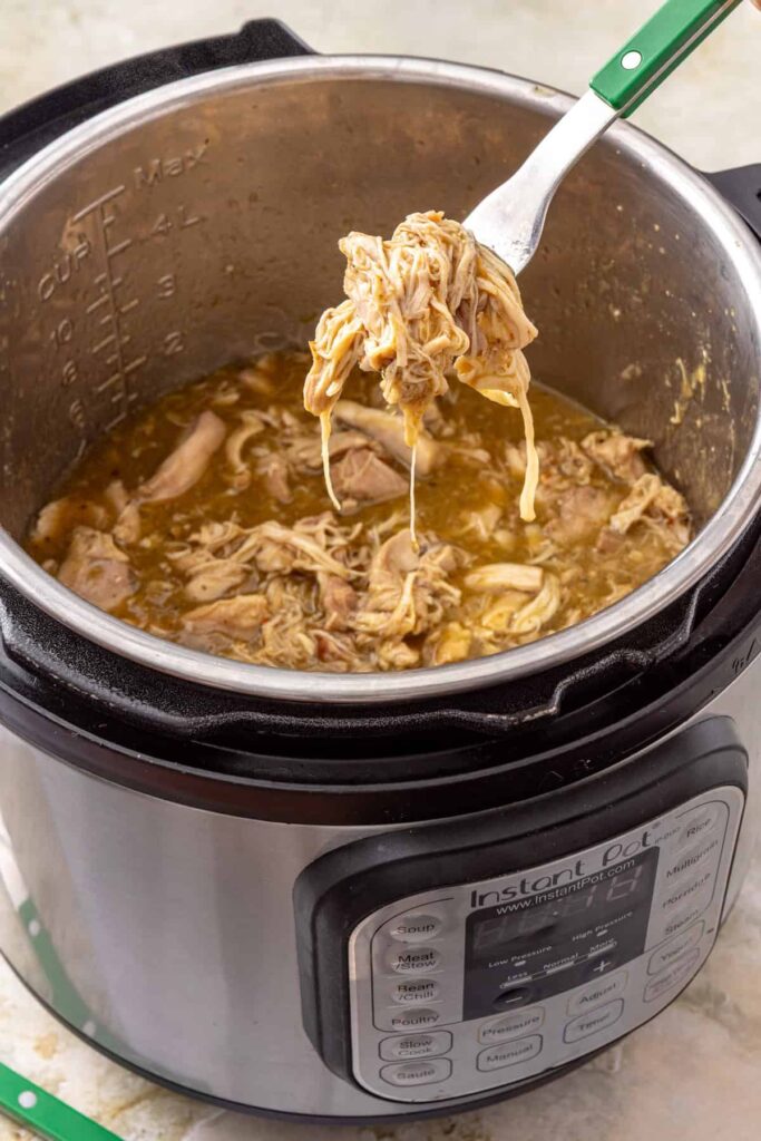 Shredding tender chicken with two forks in the Instant Pot
