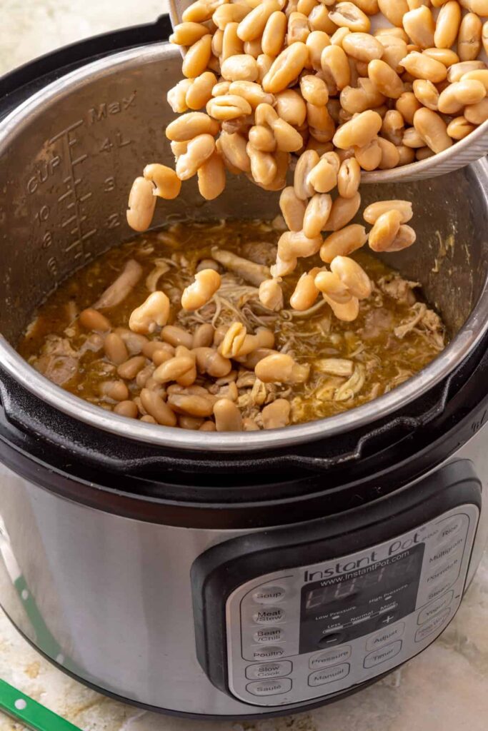 Adding white beans to shredded chicken and green enchilada sauce
