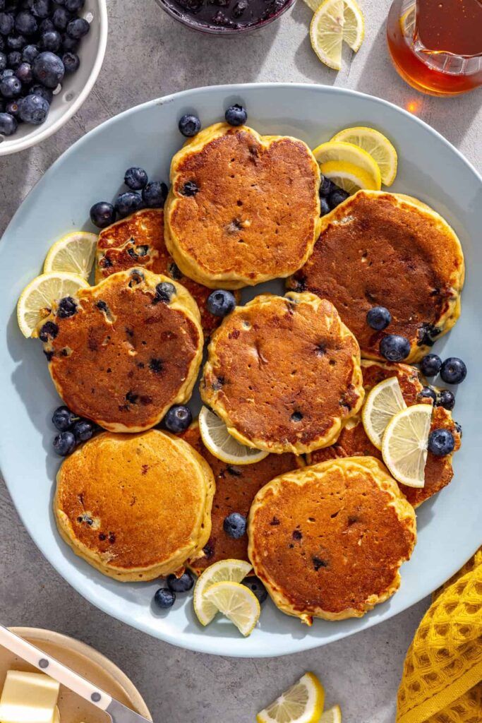 Fluffy lemon blueberry cottage cheese pancakes served on a platter with fresh blueberries and lemon slices