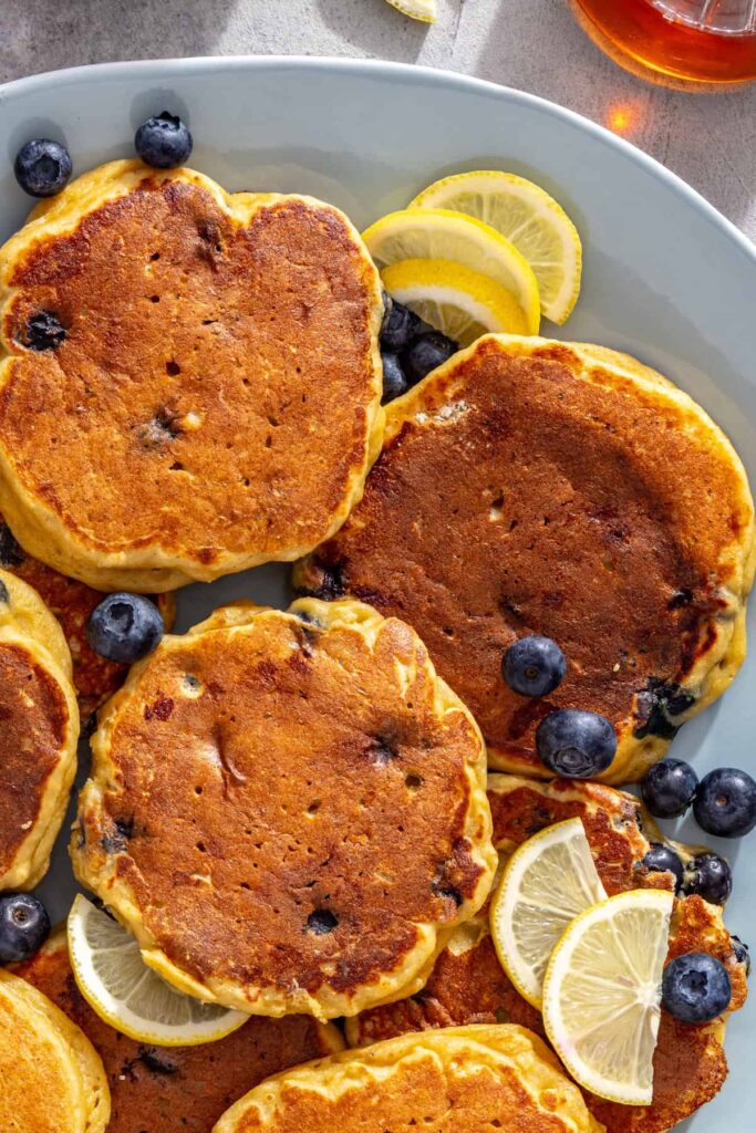 Fluffy high-protein lemon blueberry pancakes on a serving platter