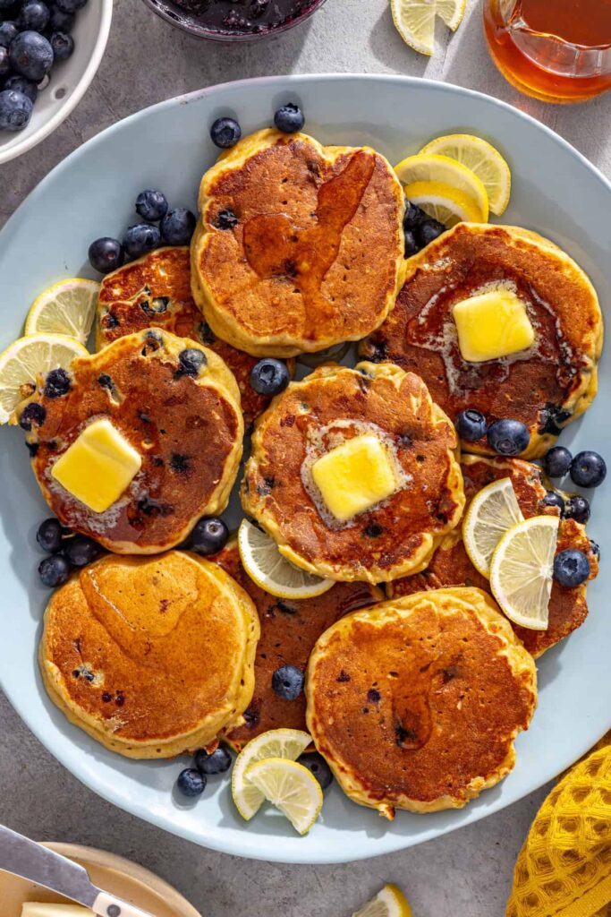 Fluffy lemon blueberry cottage cheese pancakes with melting butter, blueberries and lemon slices