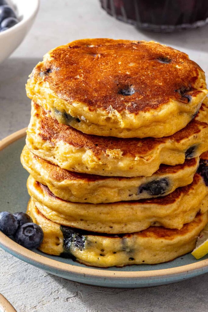Stack of fluffy lemon blueberry cottage cheese pancakes served with fresh blueberries
