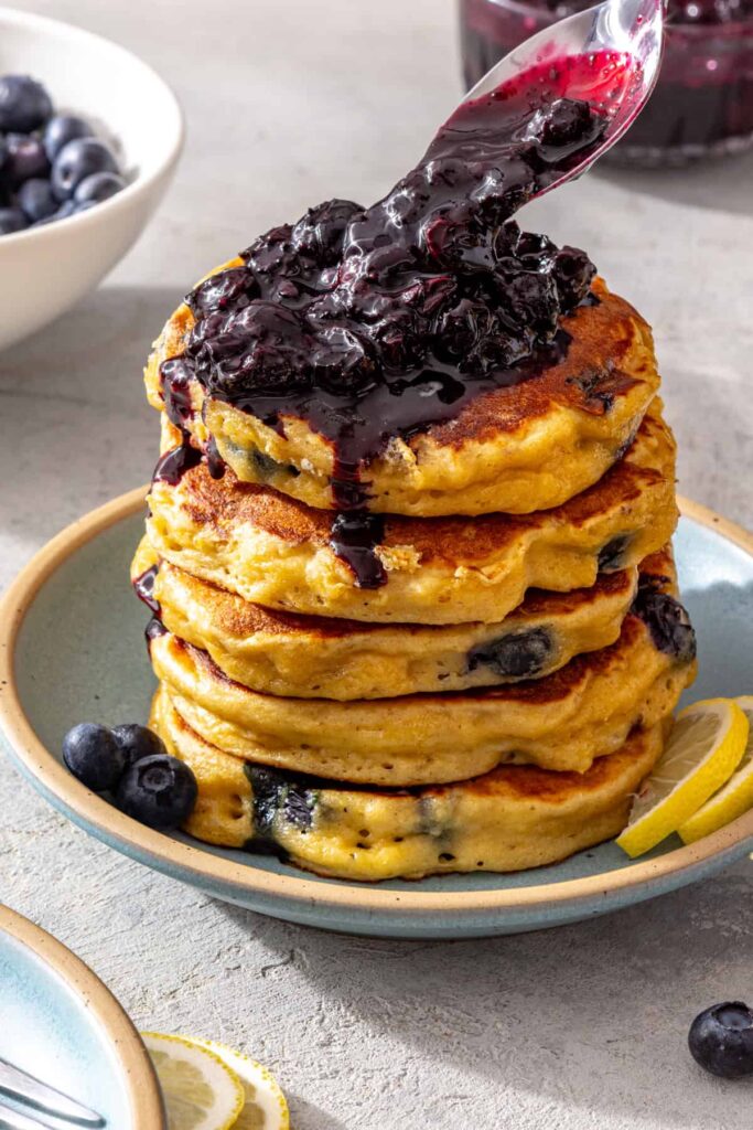 Stack of lemon blueberry cottage cheese pancakes drizzled with blueberry honey compote