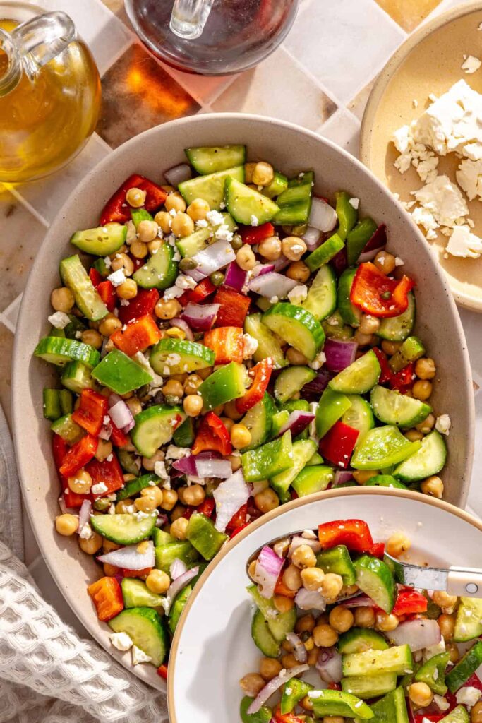Individual serving of Mediterranean chickpea chopped salad alongside a serving bowl
