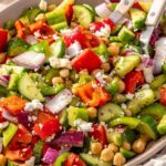 Mediterranean chickpea salad in a serving bowl with two serving utensils