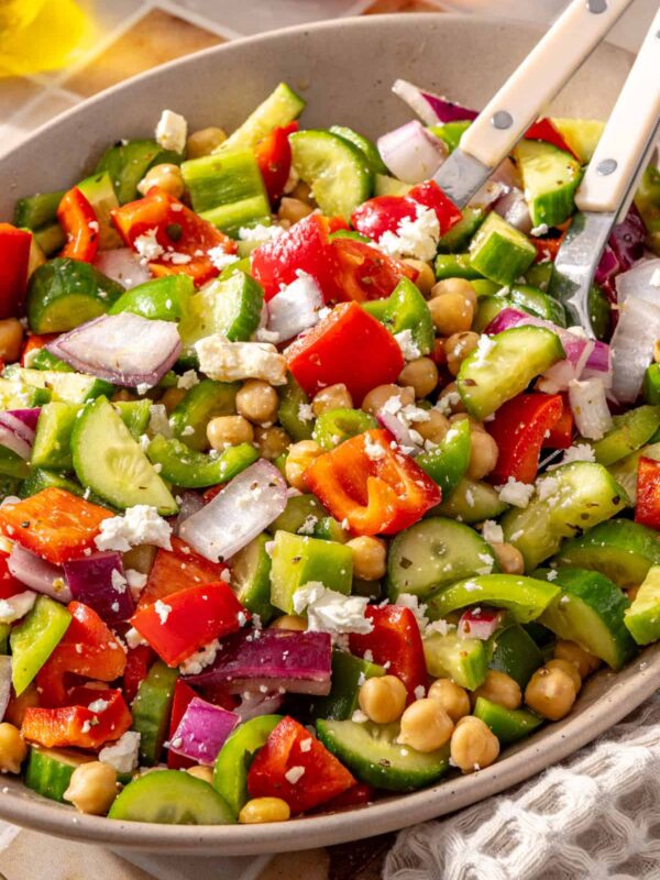 Mediterranean chickpea salad in a serving bowl with two serving utensils