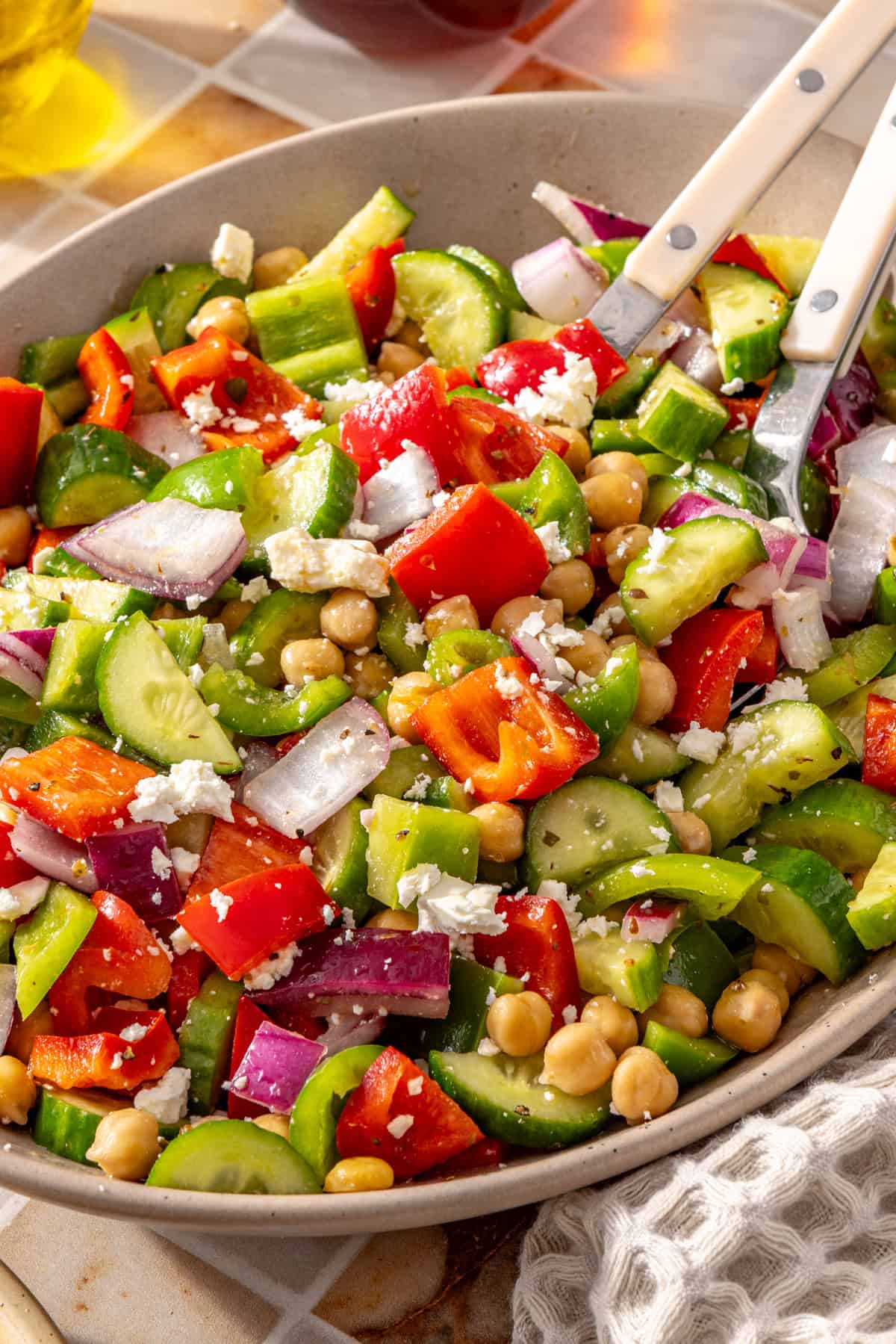 Mediterranean chickpea salad in a serving bowl with two serving utensils