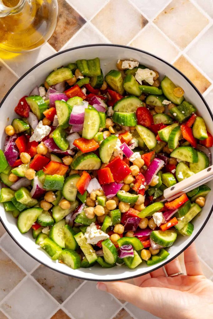 Mediterranean chickpea chopped salad in a mixing bowl with serving spoon